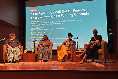 four people in a panel on a stage speaking at an event